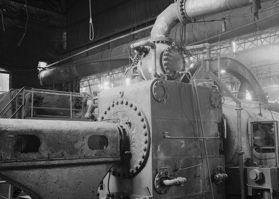 Republic Iron and Steel Company Youngstown Works, Ohio INTERIOR OF ENGINE ROOM, CONTAINING MESTA-CORLISS CROSS-COMPOUND ENGINE, FOR 40" BLOOMING MILL. THIS VIEW IS TAKEN FROM THE HIGH-PRESSURE SIDE OF THE ENGINE SHOWING THE HOUSING EXTENSION; TO THE RIGHT, IN THE BACKGROUND, IS THE 24' CAST-IRON FLYWHEEL.