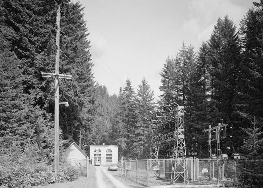Nooksack Falls Hydroelectric Plant, Glacier Washington 1987 View of the powerhouse (center), machine shop (left), and transformers (right); looking east from graveled service road into powerhouse complex