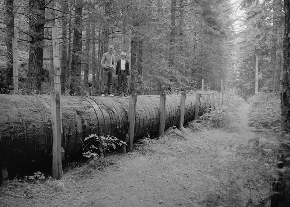Nooksack Falls Hydroelectric Plant, Glacier Washington 1987 View of wood stave penstocks (four feet in diameter) with steel bands, wood and steel frames; standing on top of penstocks is Doug Hamilton (right), Nooksack Falls Hydroelectric Plant operator for Puget Power, and Ken Rose (left) HAER Historian.