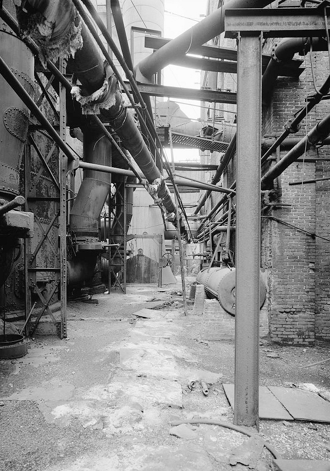 Sloss Furnace - Sloss-Sheffield Steel & Iron Company, Birmingham Alabama 1977 View looking east down areaway between hot blast stoves 25 and 26 at left and Blowing Engine House on the right