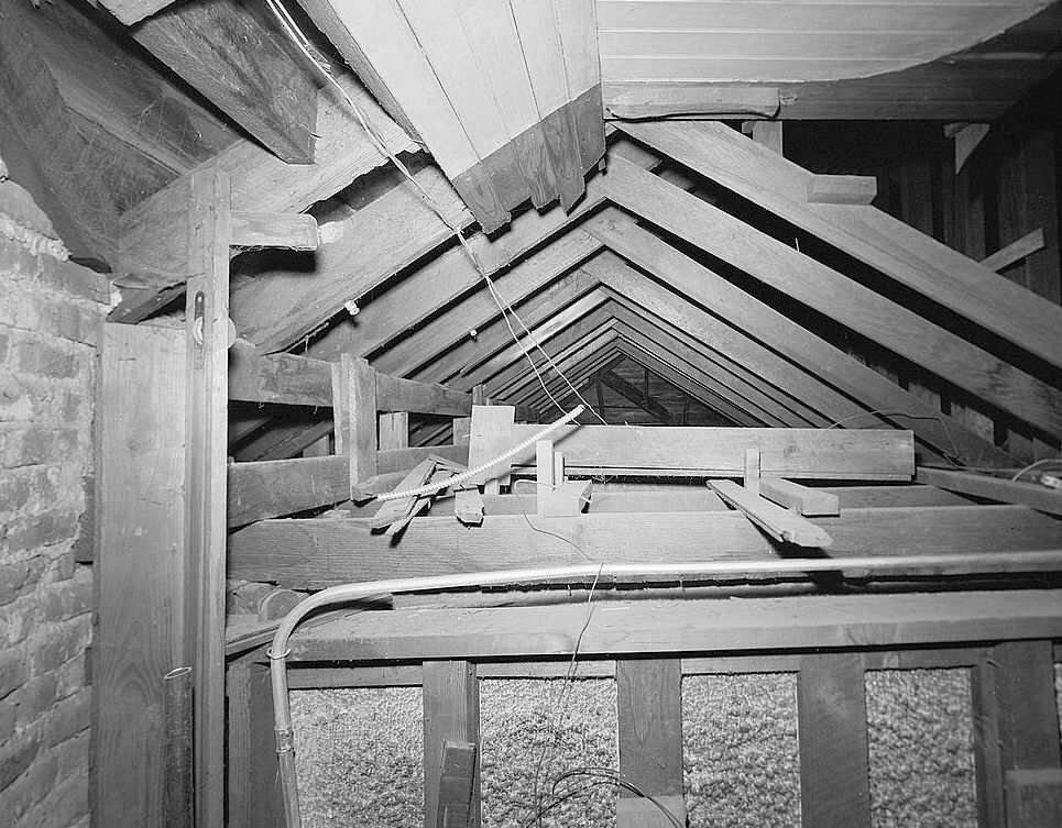 Southern Pacific Railroad Train Depot, San Carlos California 1984 Attic interior showing roof truss system over waiting room; note knob-and-tube wiring system; brick section at far left is rear of tower, which of brick masonry construction above the first story level, joined to the exterior walls of stone masonry; view to southeast along axis of building