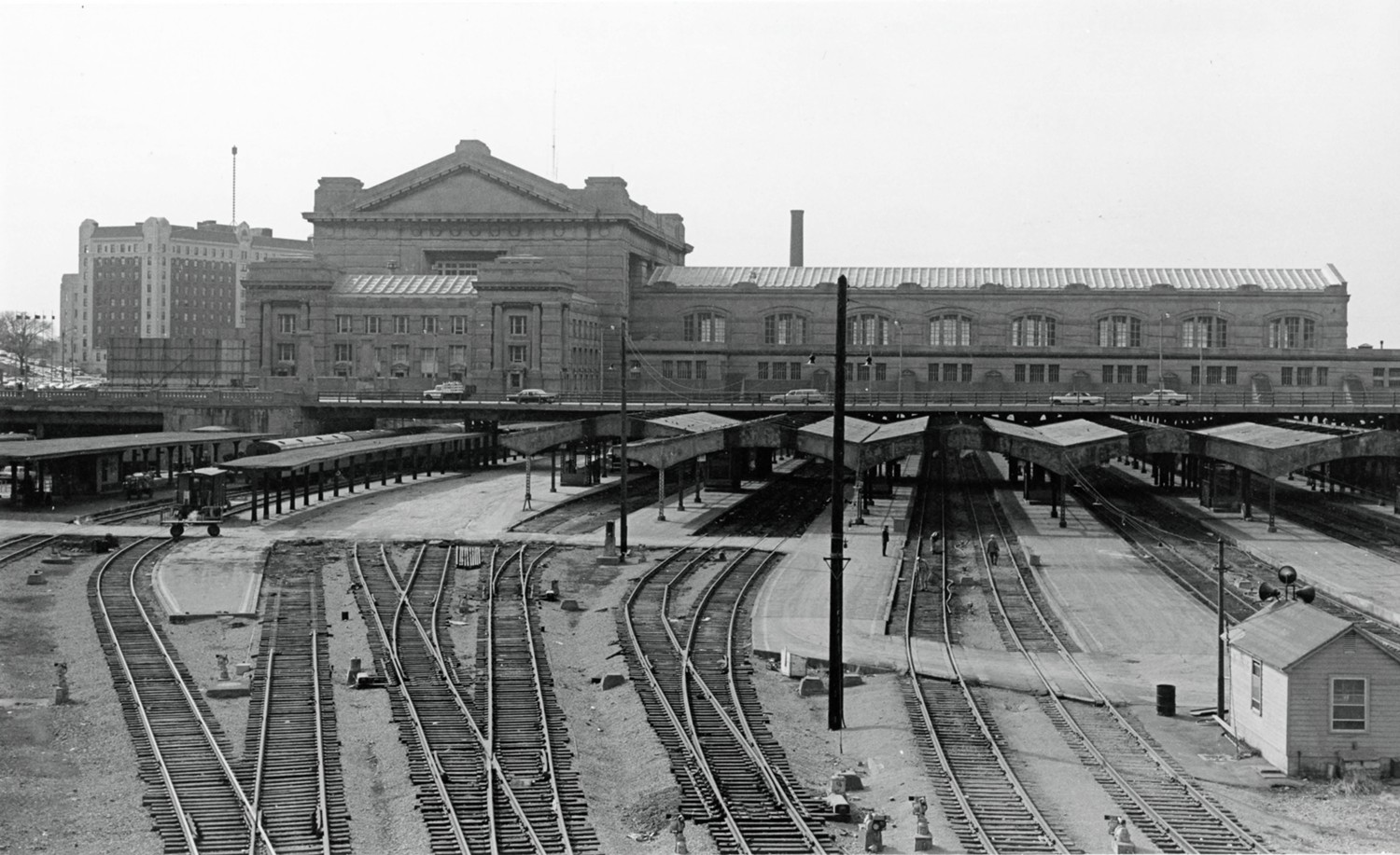 Union Station, Kansas City Missouri Front main block and east side wing at left, rear T at right, tracks with platform canopies in passenger area. Tracks pass under the rear wing and continue on the far side, making a through station. (1970)