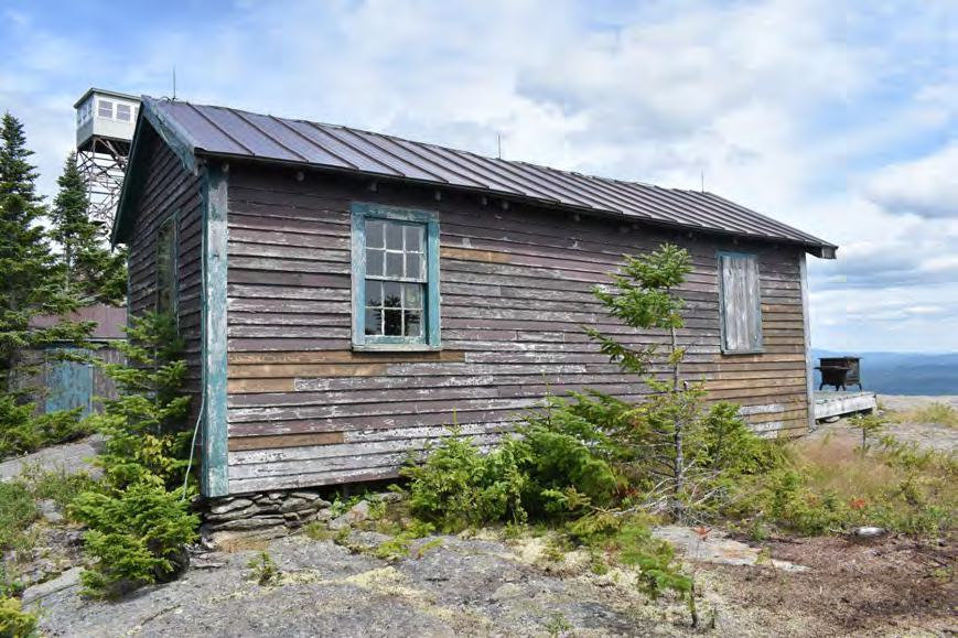 Croydon Peak Fire Tower, Newport New Hampshire Watchman's Cabin in foreground with Storage Building, Fire Tower, and Cast-Iron Stove behind (2022)