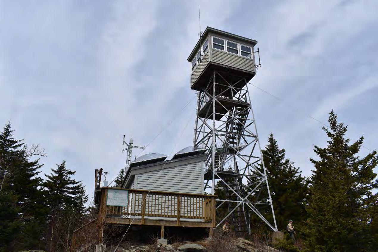 Pack Monadnock Fire Tower, Peterborough New Hampshire Diagonal stairs ascending to cab of fire tower with Ambient Air Monitoring Station at right (2022)