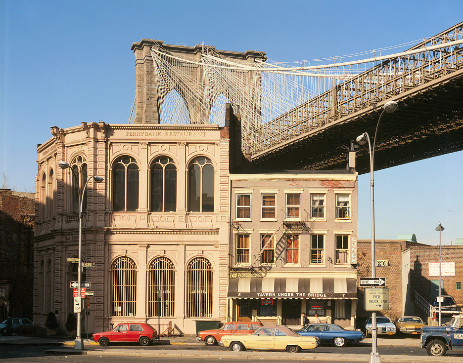 The Brooklyn Bridge, New York New York View of Brooklyn Tower Emerging behind Nineteenth Century Commercial Buildings on the Corner of Front Street and Camden Plaza (1982)