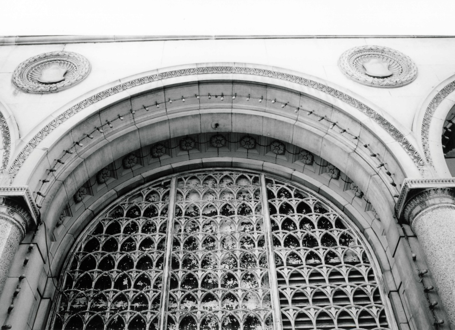 Lasalle, Koch and Company Department Store - Macys, Toledo Ohio VIEW EAST, THE METAL GRILL TYMPANUM AND TERRA COTTA BRICK-WORK INTRADOS ABOVE THE HURON STREET FACADE REVOLVING DOOR ENTRANCE (1995)