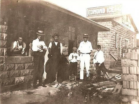 Edmond Ice Company, Edmond Oklahoma The recently completed creamery addition is visible in the background to the right of this image. In the foreground, the concrete block office building. Based on the quantity of construction materials in the image, it is likely that the photo was taken to commemorate the construction of the new building. (1921)
