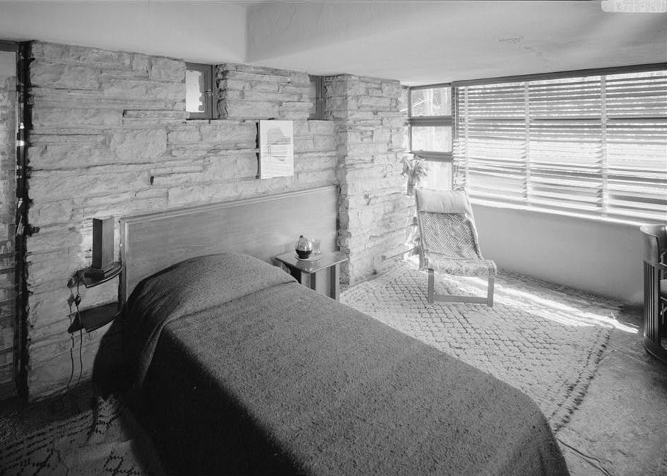 FallingWater - Frank Lloyd Wright House, Mill Run Pennsylvania EAST WALL AND SOUTH WINDOWS OF GUEST BEDROOM ON SECOND FLOOR, SHOWING BUILT-IN WALNUT HEADBOARD, SINGLE BED AND SIDE TABLE.
