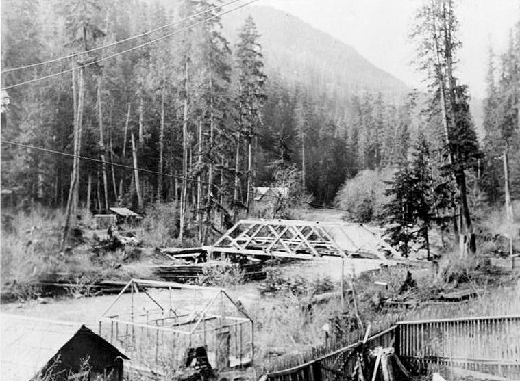 Nooksack Falls Hydroelectric Plant, Glacier Washington Historic view of modified timber king post bridge crossing the Nooksack River west of the powerhouse; Excelsior mine property on opposite side of river; looking southwest. (Photographer unknown, ca. 1904.)
